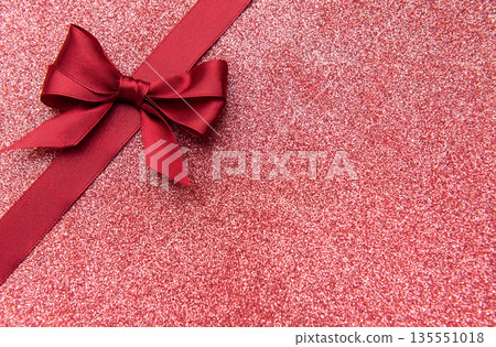 Red satin ribbon bow on sparkling glitter background Red satin ribbon bow on sparkling glitter background 135551018