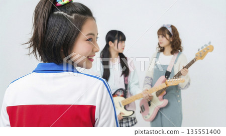 女子樂隊的成員們坐在鼓前，轉過身來微笑。 135551400