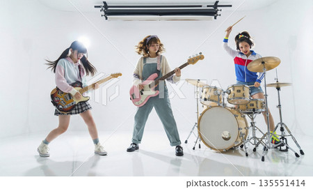 女子樂團在錄音室內表演的全身照，背景是白色，並配有燈光設備。 135551414