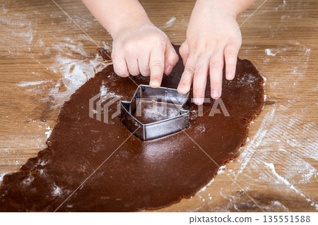 Child Cutting Gingerbread Dough With Metal Cookie Cutter On Wooden Surface Child Cutting Gingerbread Dough With Metal Cookie Cutter On Wooden Surface 135551588