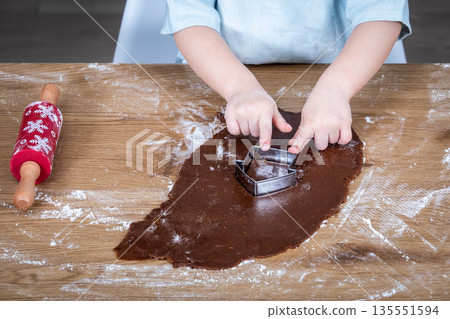 Child Cutting Gingerbread Dough With Metal Cookie Cutter On Floured Wooden Table Child Cutting Gingerbread Dough With Metal Cookie Cutter On Floured Wooden Table 135551594
