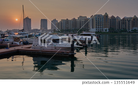 Doha, Qatar- November 15 2025: Porto Arabia Marina in The pearl sunset shot showing luxurious yachts and boats docked at the marina with  residential buildings in background. 135551649