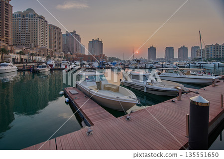 Doha, Qatar- November 15 2025: Porto Arabia Marina in The pearl sunset shot showing luxurious yachts and boats docked at the marina with  residential buildings in background. 135551650