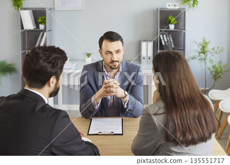 Agent and couple client serious discussion at desk, attentive and sell, buy advising, formal meeting 135551717