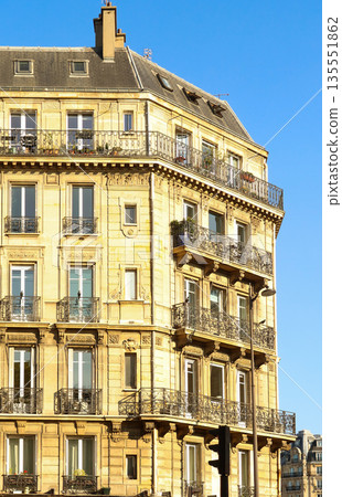Paris Haussmann building facade with balconies and detailed ironwork against blue sky Paris Haussmann building facade with balconies and detailed ironwork against blue sky 135551862