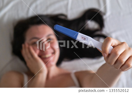 Surprised Woman with Positive Pregnancy Test 135552012