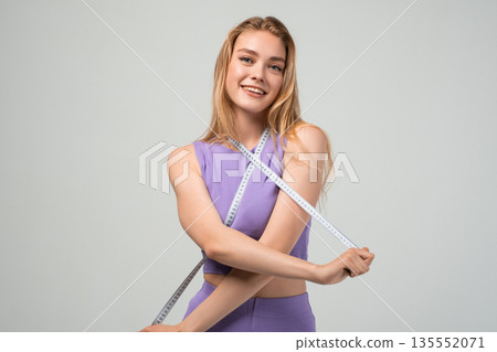 Fit young woman crossing measuring tape on body, fitness goals and weight management concept, healthy lifestyle and self control isolated on neutral background Fit young woman crossing measuring tape on body, fitness goals and weight management concept, healthy lifestyle and self control isolated on neutral background 135552071