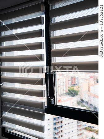 Minimalist interior window with zebra roller blinds and chain mechanism filtering daylight in modern apartment Minimalist interior window with zebra roller blinds and chain mechanism filtering daylight in modern apartment 135552121