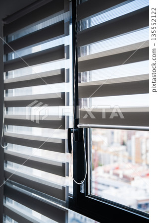 Modern zebra window blinds filtering daylight with soft city background creating clean home interior and privacy concept Modern zebra window blinds filtering daylight with soft city background creating clean home interior and privacy concept 135552122