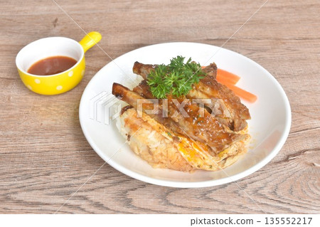 grilled pork rib dressing barbecue sauce with fried cream egg omelet on rice with boiled carrot on plate 135552217