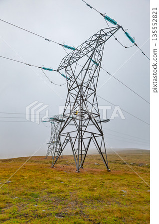 Electricity pylon and power lines in foggy moorland 135552821