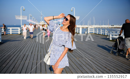 Carefree stylish woman enjoying sunny day on a seaside pier Carefree stylish woman enjoying sunny day on a seaside pier 135552917