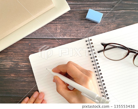 女子雙手在木桌上的筆記本上書寫。 （研究圖片） 135553438