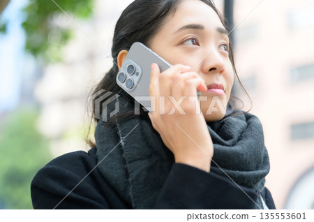 A woman wearing a scarf and using a smartphone 135553601