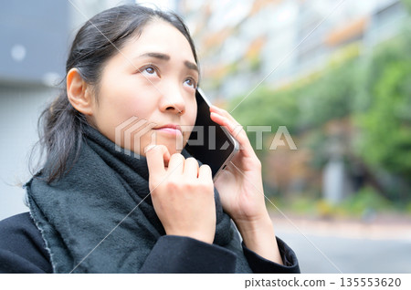 一位戴著圍巾、正在使用智慧型手機的女士 135553620