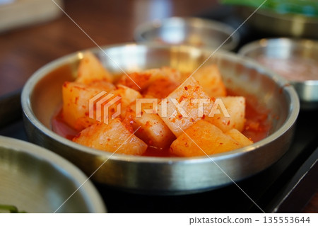 Korean radish kimchi, Kkakdugi, a popular fermented spicy side dish served in a metal bowl. 135553644