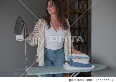 Home comfort and self care with girl ironing clean clothes and neatly stacking them creating a tidy and organized scene Home comfort and self care with girl ironing clean clothes and neatly stacking them creating a tidy and organized scene 135553695