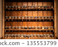 Many kind of herbal ingredients preserved inside the small vacuum glass pots on the wooden shelf. 135553799