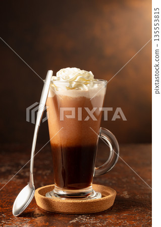 Hot chocolate with whipped cream in a glass mug. Hot chocolate with whipped cream in a glass mug. 135553815
