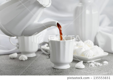 Black coffee in white porcelain cup and white small French meringues. Black coffee in white porcelain cup and white small French meringues. 135553831