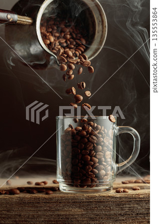 Roasted coffee beans is poured in a clear glass mug. Roasted coffee beans is poured in a clear glass mug. 135553864