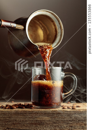 Black coffee is poured in a clear glass mug. Black coffee is poured in a clear glass mug. 135553866