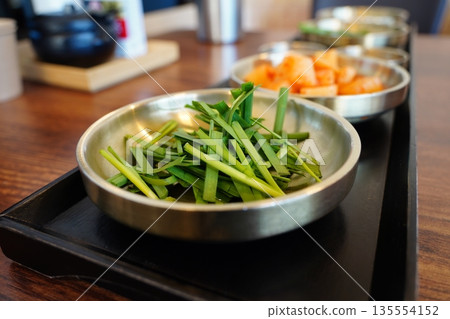 Fresh Korean garlic chives,served in a metal bowl, a popular side dish at Korean restaurants 135554152