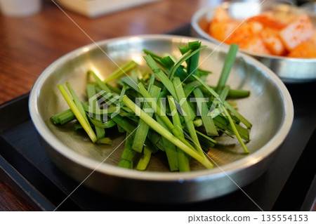 Fresh Korean garlic chives,served in a metal bowl, a popular side dish at Korean restaurants 135554153
