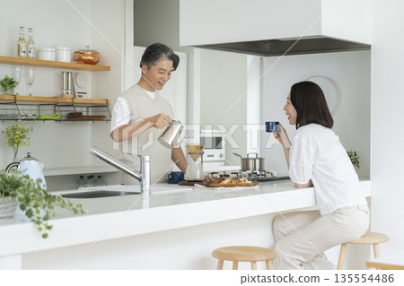 一對五十多歲的夫婦在廚房喝咖啡 一對五十多歲的夫婦在廚房喝咖啡 135554486