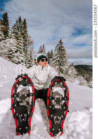 Man in Snowshoes Taking Break in Snowy Landscape Man in Snowshoes Taking Break in Snowy Landscape 135554567