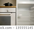 Empty Refrigerator and Built-In Oven with Pot on Stove in Modern Kitchen Interior 135555145
