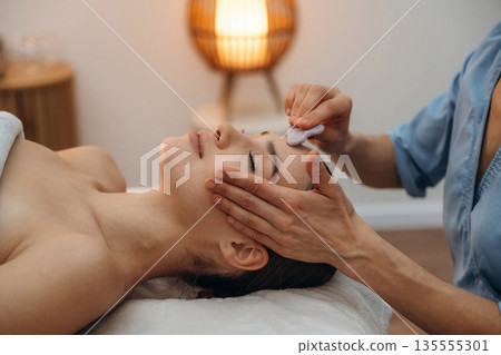 In spa salon. Relaxed young woman getting massage by therapist In spa salon. Relaxed young woman getting massage by therapist 135555301