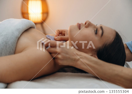 Face patches. Relaxed young woman getting massage by therapist in spa salon Face patches. Relaxed young woman getting massage by therapist in spa salon 135555304