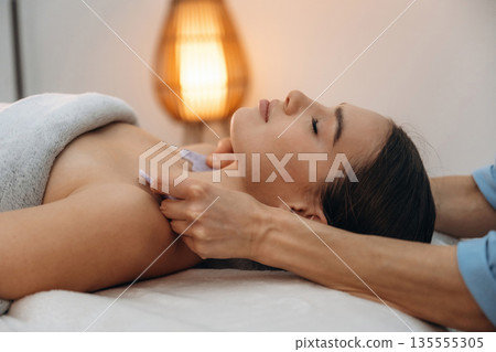 Face patches. Relaxed young woman getting massage by therapist in spa salon Face patches. Relaxed young woman getting massage by therapist in spa salon 135555305