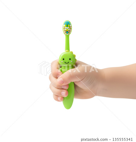 Close-up of a small toddler's hand firmly gripping a green fun dinosaur or t-rex themed toothbrush, promoting early dental care habits Close-up of a small toddler's hand firmly gripping a green fun dinosaur or t-rex themed toothbrush, promoting early dental care habits 135555341
