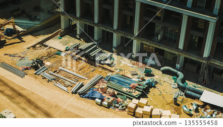 Aerial view of resort construction site with heavy machinery and partially built structures Aerial view of resort construction site with heavy machinery and partially built structures 135555458