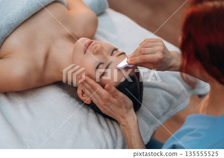 Facial massage. Relaxed young woman is with therapist in spa salon Facial massage. Relaxed young woman is with therapist in spa salon 135555525