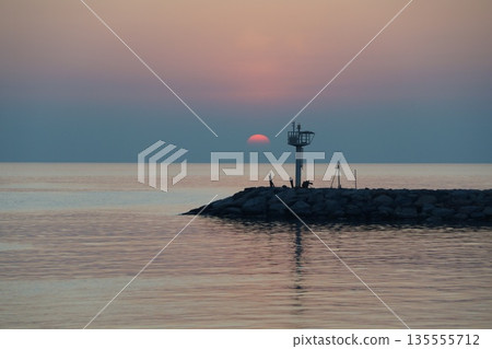 golden dawn on the sea.The dawn of a red dawn on the horizon of the sky, beyond a stone pier. golden dawn on the sea.The dawn of a red dawn on the horizon of the sky, beyond a stone pier. 135555712
