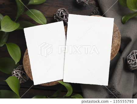 Vertical cards mockup on brown wooden tray near green leaves and grey linen cloth top view Vertical cards mockup on brown wooden tray near green leaves and grey linen cloth top view 135555793