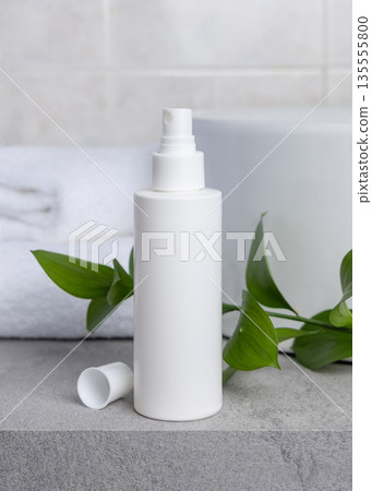 White blank cream bottle near green leaves, basin and white bath towels on grey stone, mockup White blank cream bottle near green leaves, basin and white bath towels on grey stone, mockup 135555800
