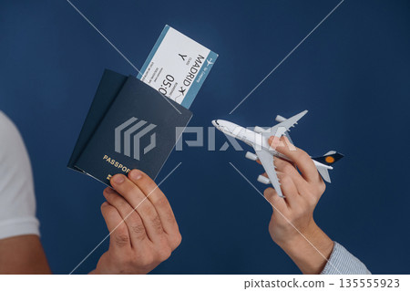 Ticket and toy plane. Close up view of woman's and man's hands that are ready for vacation Ticket and toy plane. Close up view of woman's and man's hands that are ready for vacation 135555923