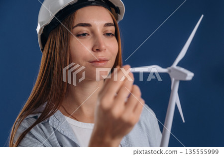 Touching the wind. Woman engineer electrician is holding toy wind generator Touching the wind. Woman engineer electrician is holding toy wind generator 135555999