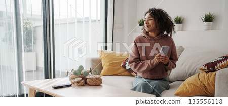 Woman Enjoys Tranquil Creative Moment, Independent Woman Relaxes Amid Plants And Soft Sunlight Woman Enjoys Tranquil Creative Moment, Independent Woman Relaxes Amid Plants And Soft Sunlight 135556118