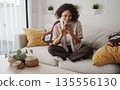 African American Woman Enjoying Morning, Woman Sitting Comfortably On Sofa With Coffee And Plants 135556130