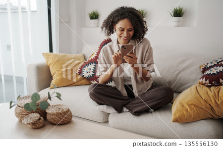 African American Woman Enjoying Morning, Woman Sitting Comfortably On Sofa With Coffee And Plants African American Woman Enjoying Morning, Woman Sitting Comfortably On Sofa With Coffee And Plants 135556130