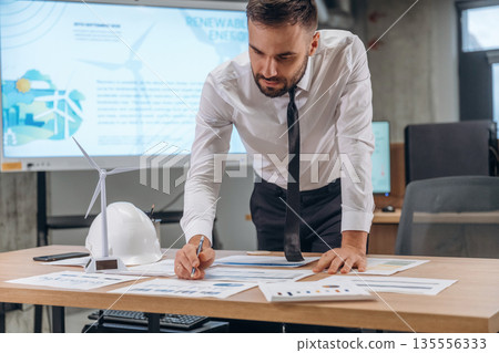 Paperwork, writing on graphs. Man is working in the wind turbine company Paperwork, writing on graphs. Man is working in the wind turbine company 135556333