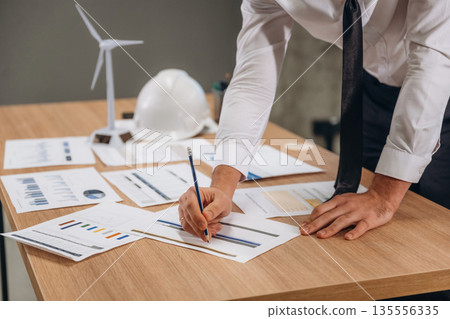 By the table with documents. Man is working in the wind turbine company By the table with documents. Man is working in the wind turbine company 135556335