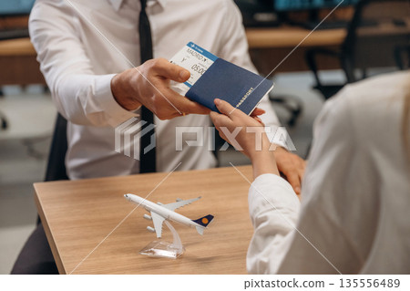 Travel and vacation time. Woman is giving boarding pass, tickets to airline company worker Travel and vacation time. Woman is giving boarding pass, tickets to airline company worker 135556489