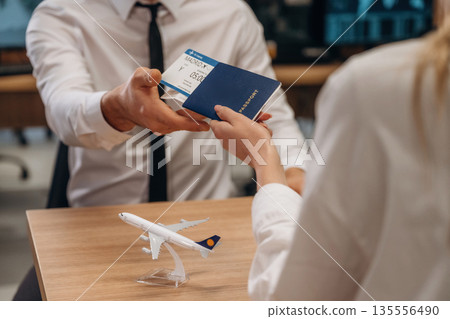 Travel and vacation time. Woman is giving boarding pass, tickets to airline company worker 135556490