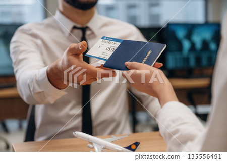 Travel and vacation time. Woman is giving boarding pass, tickets to airline company worker Travel and vacation time. Woman is giving boarding pass, tickets to airline company worker 135556491